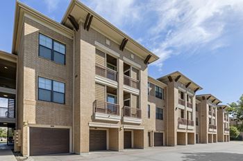 a brick apartment building with garages and a blue sky